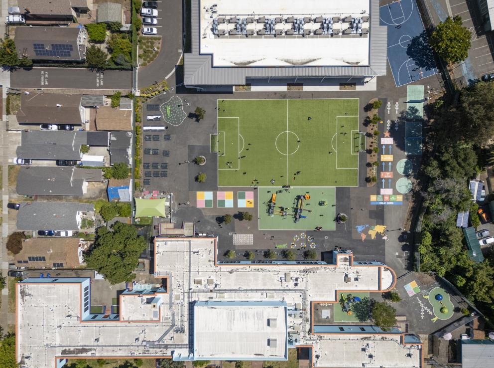 Drone aerial view of Achieve Academy showing the Oakland campus, new classroom building, play areas, and surrounding neighborhood context